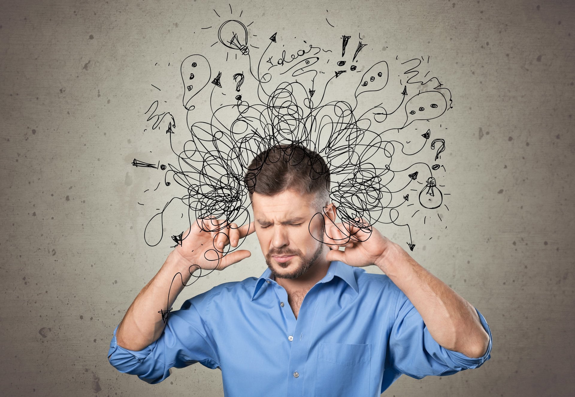 A man in a blue shirt covers his ears, appearing stressed or overwhelmed. Black doodles of tangled lines, question marks, and lightbulbs surround his head, symbolizing confusion and mental chaos. The background is a plain grayish wall.