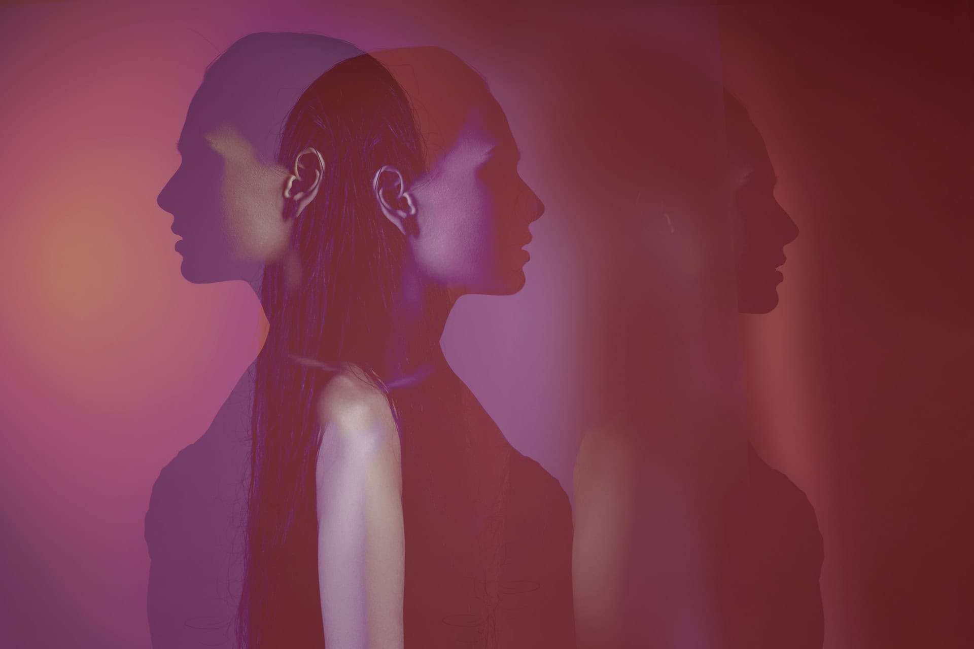 A stylized image features a womans profile with double exposure effects, creating overlapping silhouettes in shades of purple, pink, and red. The background is softly blurred, enhancing the dreamy, artistic atmosphere.